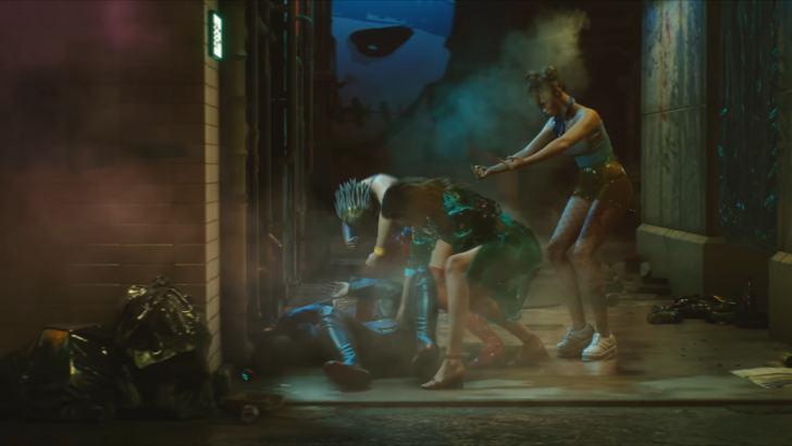 The screenshot shows a Cyberpunk 2077 scene where two women brutally assault a man while a third woman incessantly flips him the bird with both hands