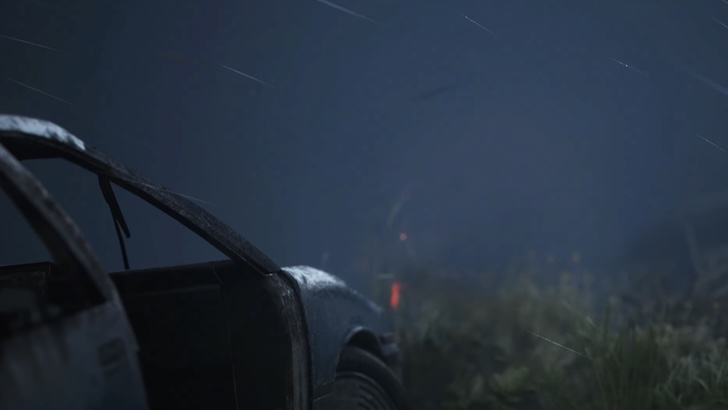 A damaged vehicle sits in tall grass under heavy rain